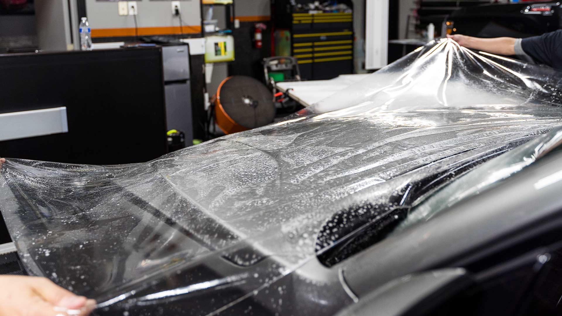 STEK PPF being wrapped onto the rear quarter panel of a red sports car during SSF Detail install