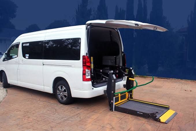 Driver assisting a wheelchair user boarding an accessible van