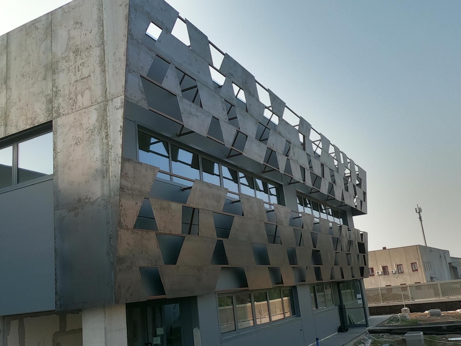 Facciata con pannelli metallici geometrici su telaio — vista d'insieme