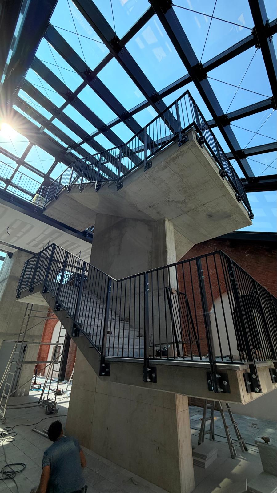 Scala con parapetti in ferro nero sotto copertura vetrata — seconda vista