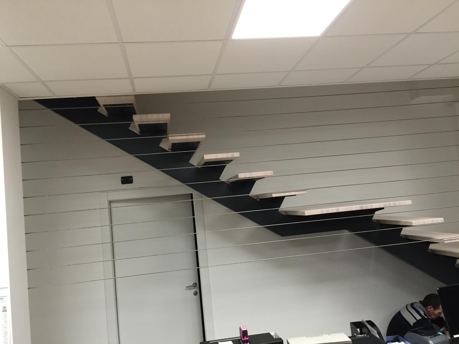 Scala sospesa a giorno con monoscivolo nero e pedate in legno