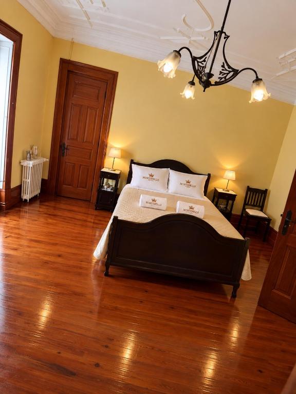Quarto amarelo com cama de casal em madeira escura e candeeiro de teto