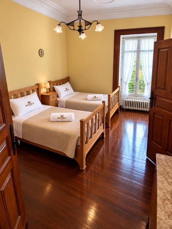 Quarto amarelo com duas camas individuais em pinho e candeeiro de teto