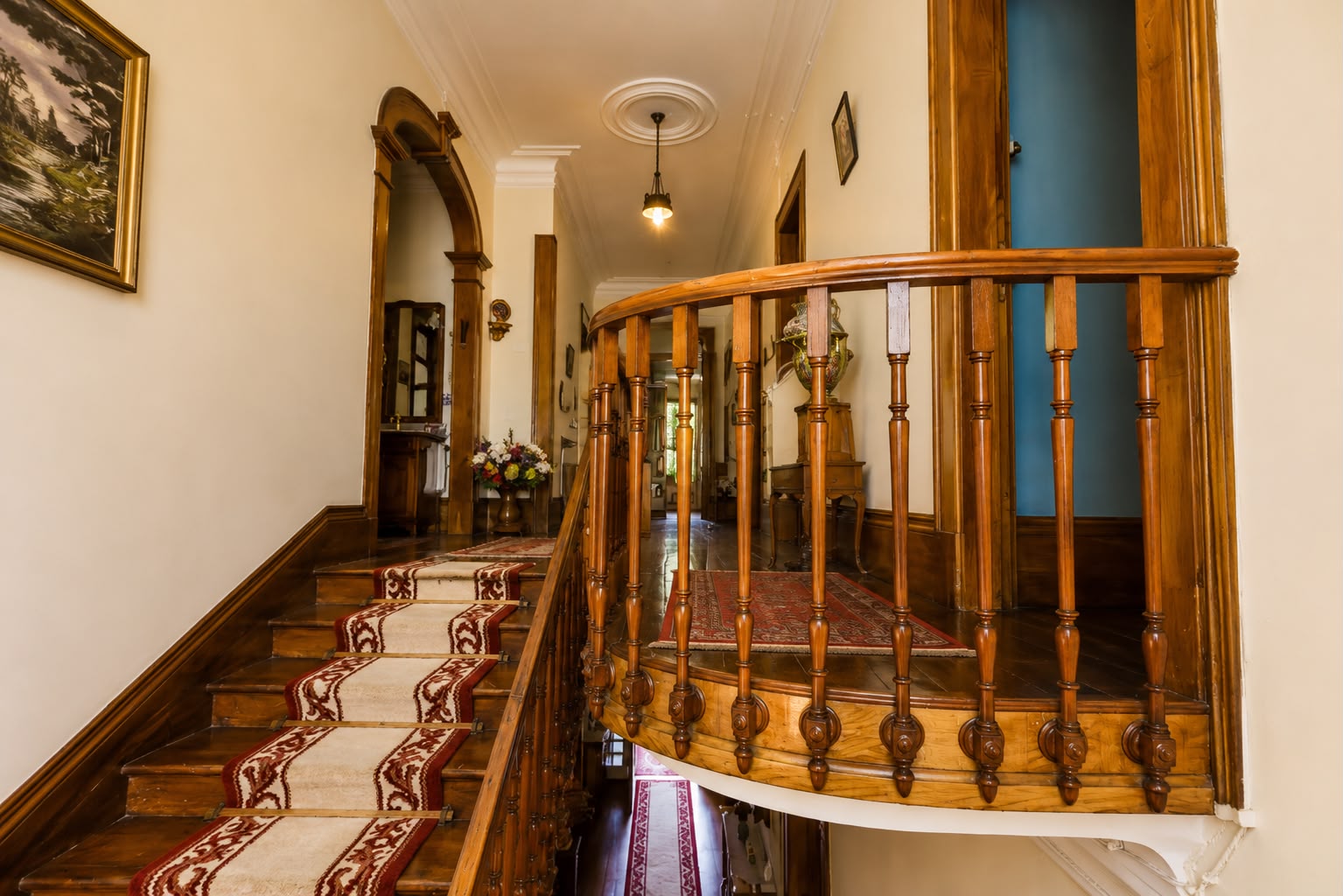 Escadaria com corrimão de madeira e tapete clássico