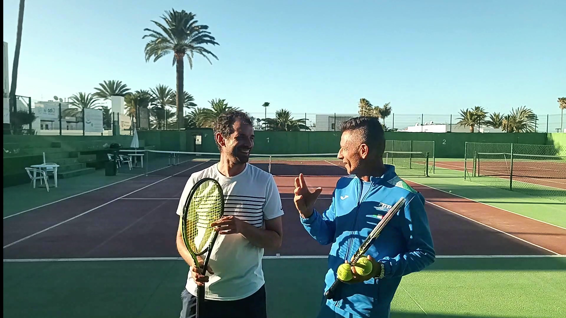 Edoardo Pozzi discussing a player’s tennis on court, wearing his FITP coaching jacket