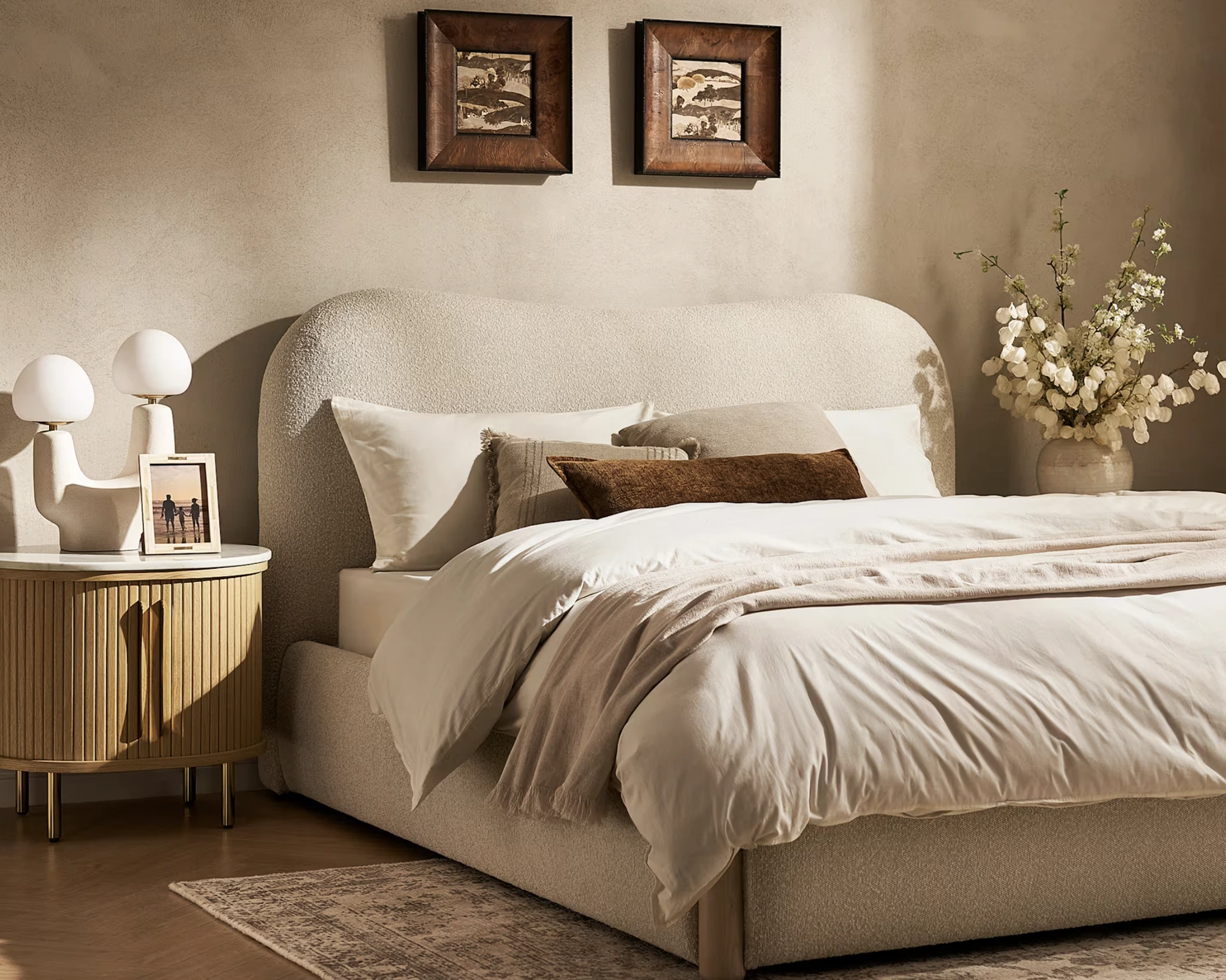 Calm bedroom with a soft upholstered bed, linen bedding and a bedside table in warm daylight